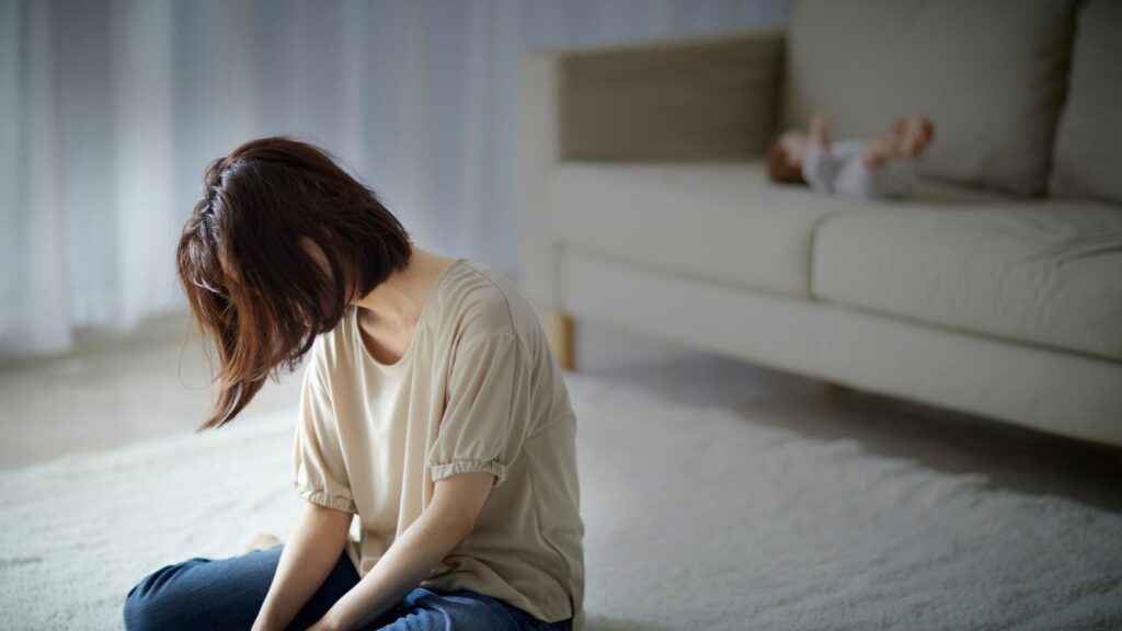 心の限界を感じながら床に座り込む女性