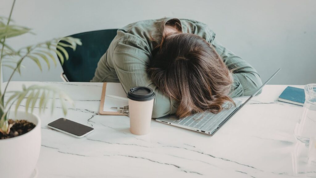 疲れとストレスで机に突っ伏す女性の様子