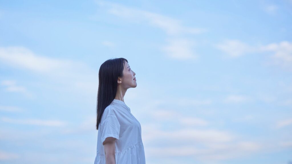 空を見上げながら静かにたたずむ女性の横顔
